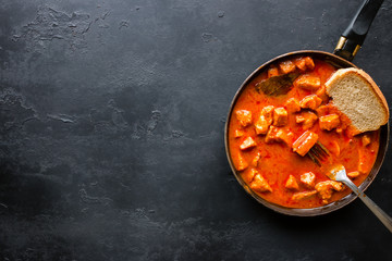 Stew with bread in a frying pan on a black background