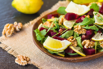 Salad with arugula, beets and nuts in a wooden plate