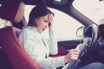 Stressed desperate woman driver with documents sitting inside her car