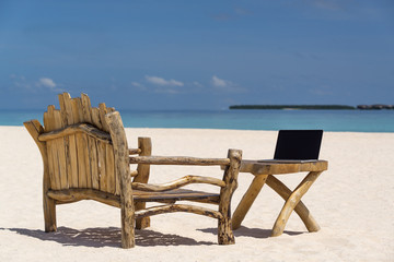 Fototapeta na wymiar laptop blank screen on wooden desk with beach. relax concept.