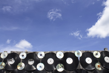 Vinyl and cd screwed to a fence against a blue sky background