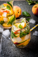 Summer refreshment drinks. Peach mojito with lime, peach and mint. With the ingredients on a dark stone table.  copy space