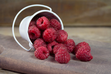 Fresh raspberrys  in a can. Spill over the wooden board