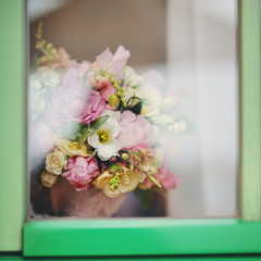 Сolor wedding bouquet against the background of a white curtain. A color bouquet of the bride, love and romanticism, a gift outside the window in a green frame