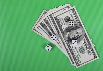 Gambling dice and hundred dollar bills on green background and texture