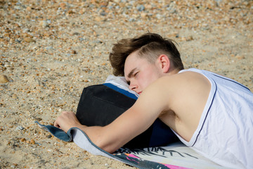 Teenage boy laying on a stoney beach