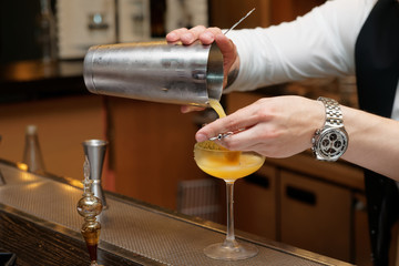 Fototapeta na wymiar Bartender is pouring cocktail from shaker