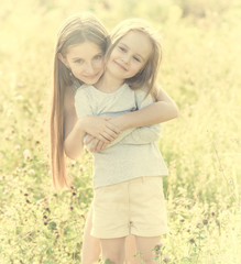 sibling sisters hugging each in the field