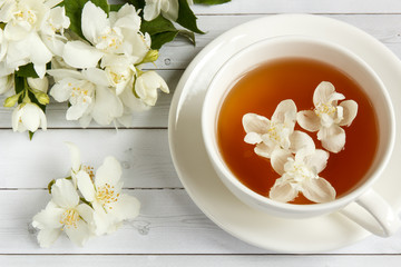 Cup of tea with jasmine flowers on a wooden background