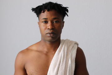 Schwarzer junger Mann mit Handtuch vor weißem Hintergrund