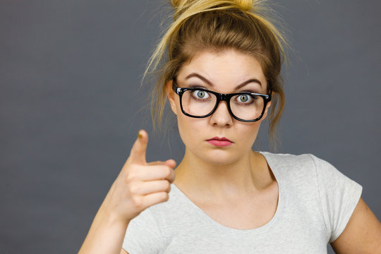 Woman wearing eyeglasses pointing at camera