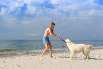 happy girl playing with a dog on the beach