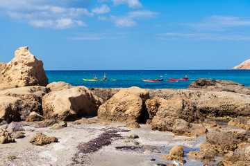 Fototapeta na wymiar Tourists kayaking near Firiplaka Beach, one of the most popular beach situated at the southern side in Milos island. Cyclades, Greece. 