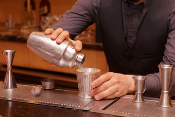 Bartender is pouring cocktail into a glass