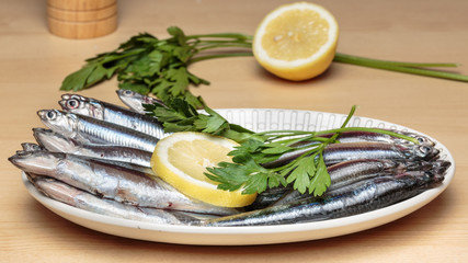 Oval dish full of fresh Mediterranean anchovies, known as 