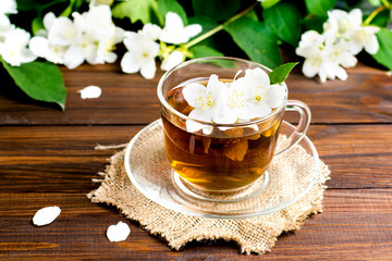Fragrant tea with jasmine in a glass cup on a wooden table.