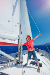 Fototapeta premium Little boy captain on board of sailing yacht on summer cruise. Travel adventure, yachting with child on family vacation.