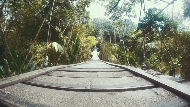 Establishing shot of a rickety wood and rope bridge over a jungle valley.