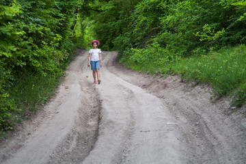 girl in shorts and a hat walking in the summer on a country road