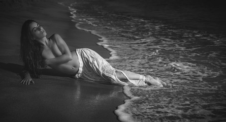 Fototapeta premium Elegant Beautiful brunette woman with long white skirt on the beach in spain