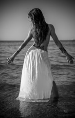 Fototapeta na wymiar Power sensual Beautiful brunette woman with long white skirt on the beach in spain