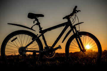 Naklejka na ściany i meble Silhouette of mountain bicycle on the sunset background