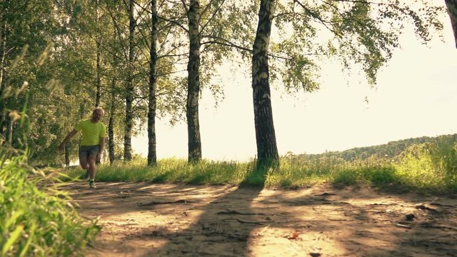 Slow Motion Shot Of An Athletic Runner Stumbling And Twisting His Ankle On The Forest Road While Running