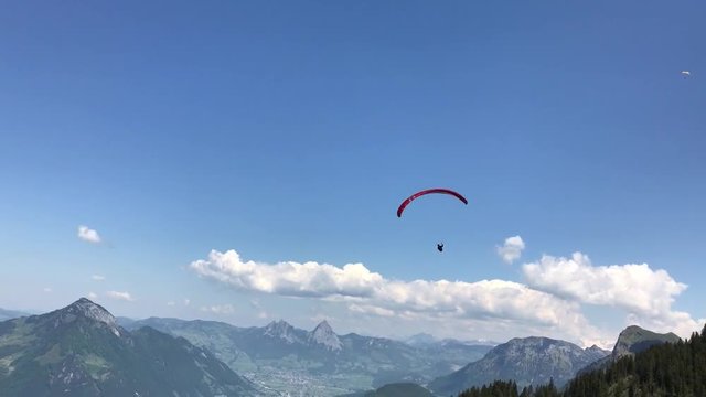 Paragleiter - Gleitschirm fliegt am blauen Himmel über dem Vierwaldstättersee und den Alpen der Zentralschweiz
