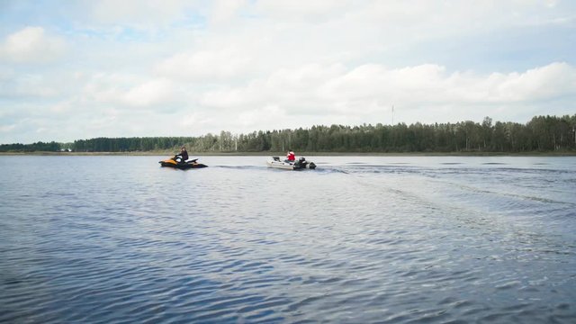 Jet Ski with boat on rope tow on lake or river. Forest background teal and orange 4k uhd. Fast movement.