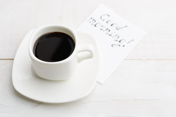 Simple morning with white cup of coffee for better half with 'good morning' message on white wooden table