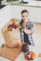 Young woman holding grocery shopping bag with vegetables .