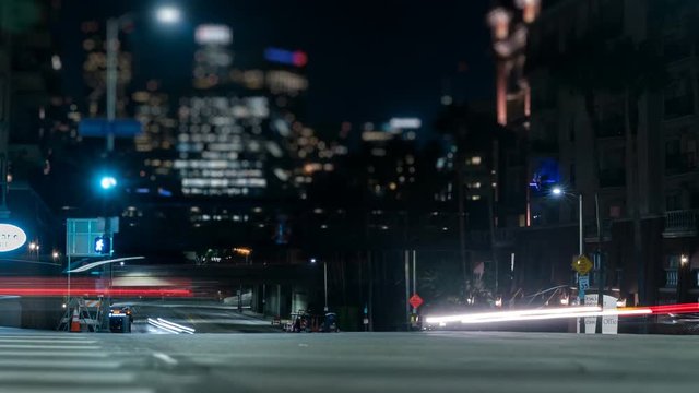 DTLA Intersection Tilt-shift. Traffic blurs past in fast motion through a busy intersection at night near downtown Los Angeles, California.