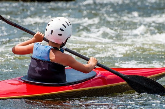 A teenager trains in the art of kayaking. Slalom boats on rough river rapids. The child is skillfully engaged in rafting.