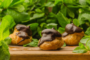 French eclairs covered with chocolade on wooden board
