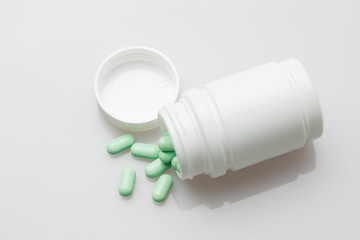 Pills and pill bottle on white background