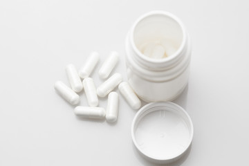 Pills and pill bottle on white background