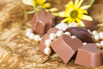 Chocolates and pearls on golden background