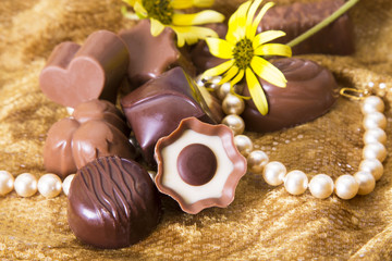 Obraz na płótnie Canvas Chocolates and pearls on golden background