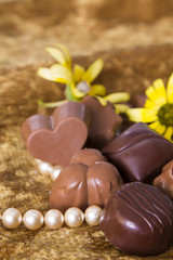 Chocolates and pearls on golden background
