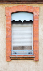 Old light blue sliding closed window shutters. Red bricks window frame