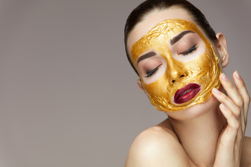 Cosmetic Mask. Beautiful Woman With Gold Mask Touching Face