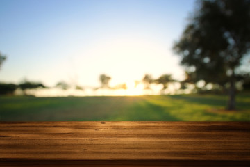 Empty wooden table in front of dreamy countryside sunset background