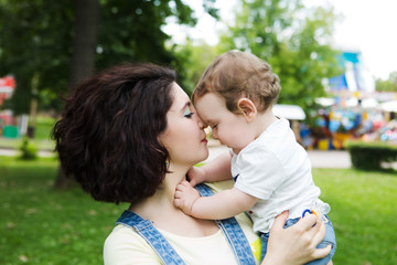 Portrait of happy loving mother and her baby boy playing in park. happy family outdoors.