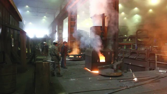 Melting iron is processing in smoky and hard working, polluted environment at the foundry shop.