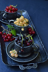 Composition of fresh ripe berries: red, black and white currants on a dark gray concrete background. Dark photo. Photographing in natural light. Space for your text