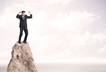 Happy businessman standing on cliff