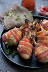 Oven-baked chicken legs wrapped in bacon, close-up, vertical shot