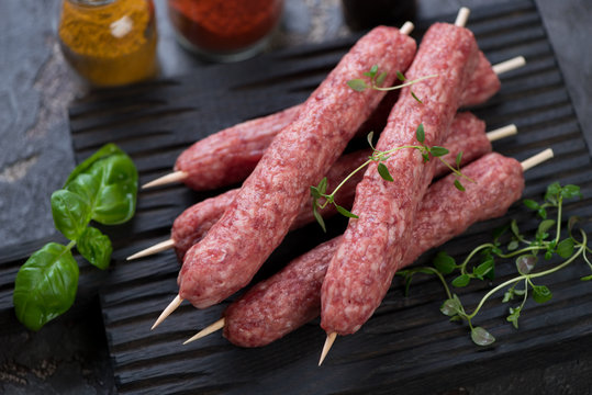 Raw cevapcici or skinless beef sausages on skewers, traditional dish in the Balkans. Close-up, selective focus