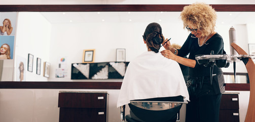 Female hair stylist working on a woman 's hair at salon