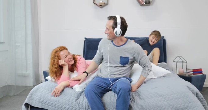 Happy Family Using New Headphones Listening To Music In Bedroom Spending Time Together In Morning Slow Motion 60
